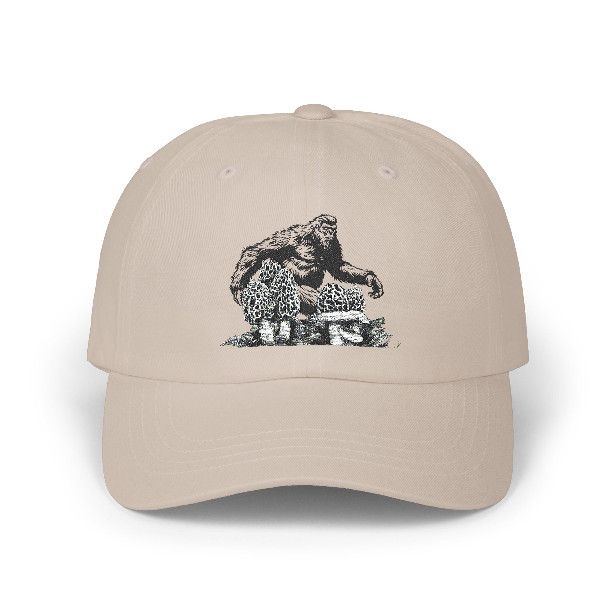 Beige cap with a black and white graphic of a bigfoot and morel mushrooms on a white background