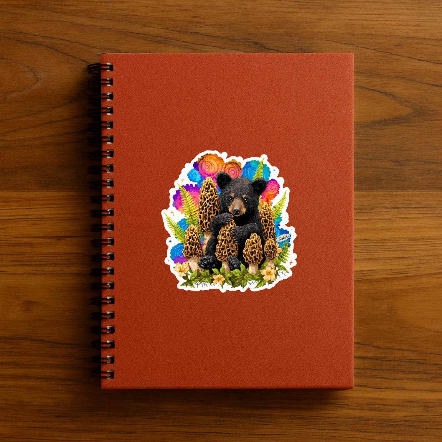 Red notebook with a colorful bear illustration on a wooden surface